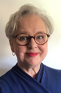 leende kvinna med kort grått hår och glasögon
