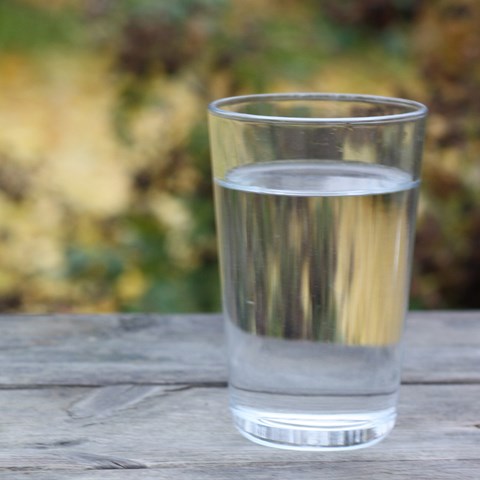 Ett glas vatten står på en bänk.