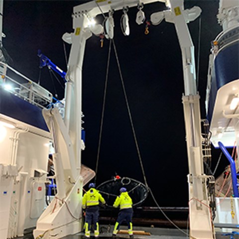 En trål för fisklarver sätts i från akterdäck på forskningsfartyget Svea, mitt i natten, av två matroser  med  reflexjackor. Foto.