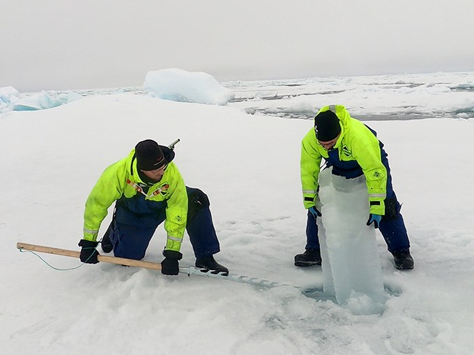 Två män som borrar hål i isen 