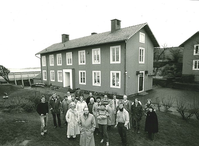 En grupp människor står framför ett hus 1984. Foto.