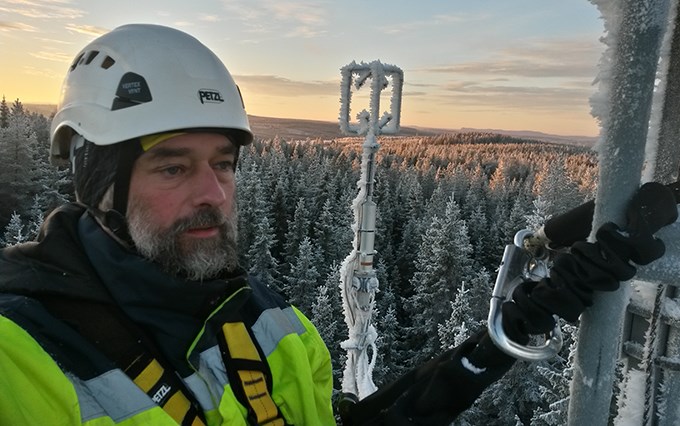 Man högt uppe i mast, mycket snö.