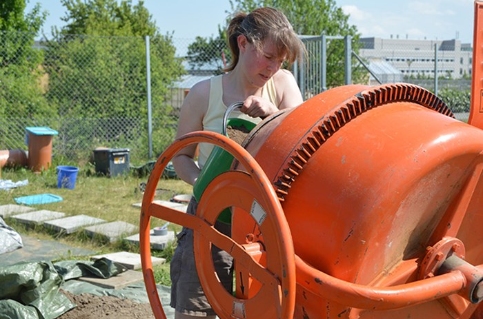 Woman working with cement mixer.