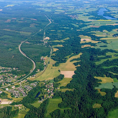 Landskap med skog, åkrar, sjö och stad. Flygfoto.