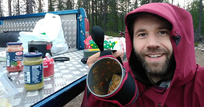 Man med huva äter middag ute.