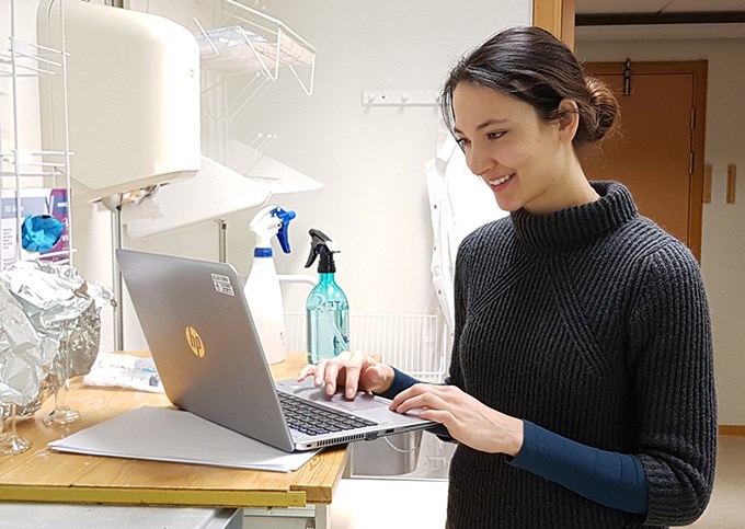 Kvinna skriver på en laptop i labbet.