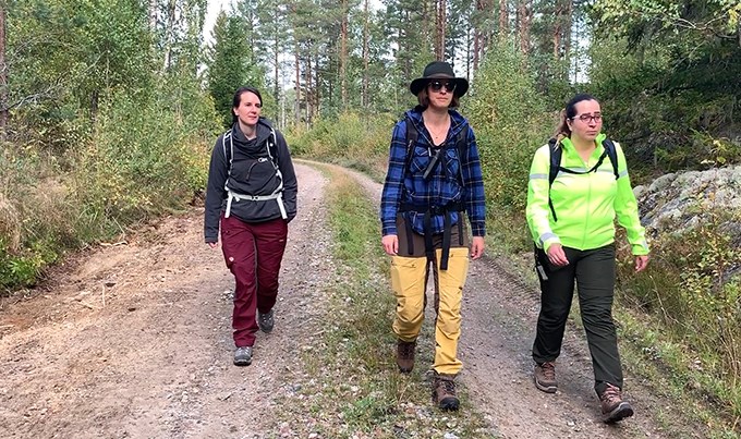 Tre kvinnor går på skogsväg.