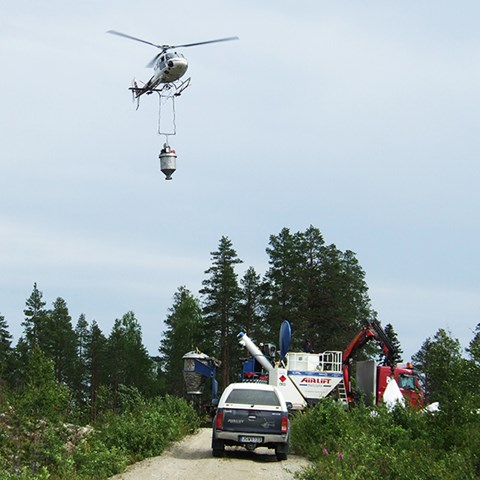Helikopter flyger över skog.