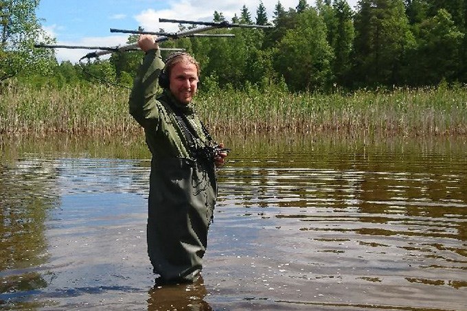 Man står i vatten med en antenn i handen.
