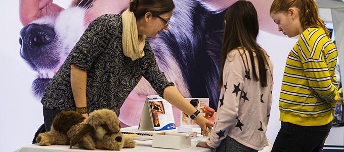 Man talking to a child - large picture of a dog in the background.