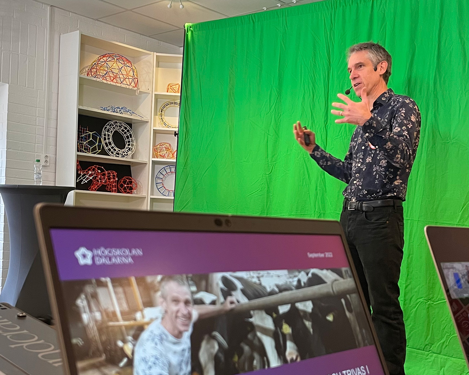A man is talking in front of a green screen.