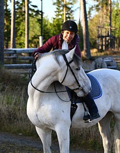 Foto: Kvinna rider på en vit häst