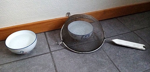 Foto: Två vattenskålar på golvet, den ena övertäckt med ett upp-och-ned-vänt durkslag