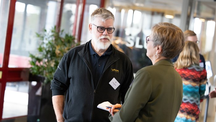 Man med grått skägg och glasögon pratar