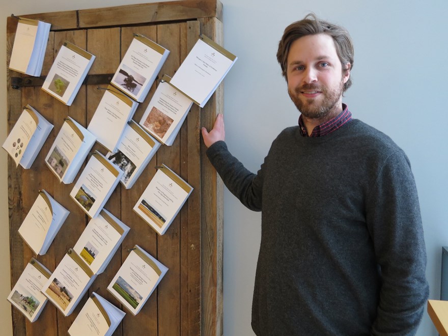 A person in front of a wall full of books that has been nailed to the wall, photo.