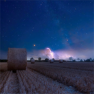 Höbalar på ett fält under en stjärnhimmel, foto.