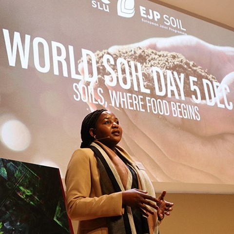 Researcher Grace Kangara at the stage in front of a screen