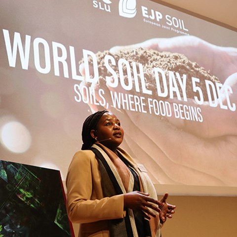 Forskaren Grace Kangara på scenen framför en storbildsskärm