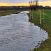stream by agricultural field with sunset in the background