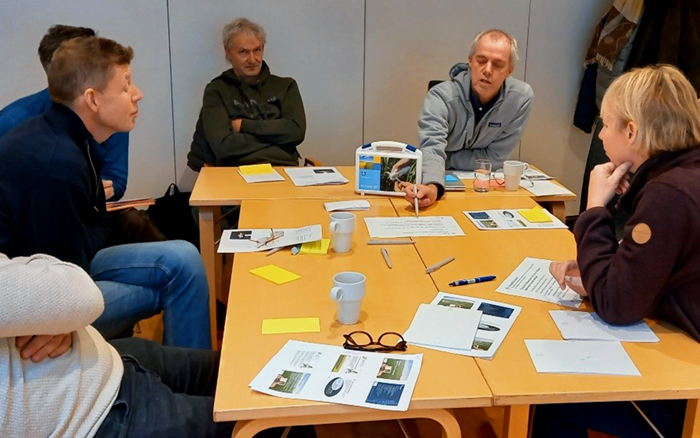 fem eprsoner runt ett bord med anteckningsblock