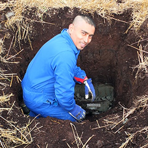 En man i blå kläder i ett stort hål i marken, foto.