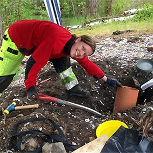 A woman in a red jacket digs a hole in the ground, photo.