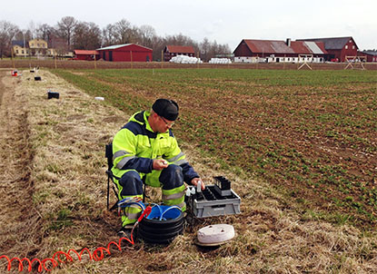 En man med mätinstrument på en åker, foto.