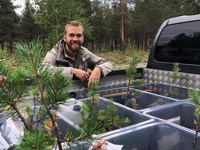 man bakom lastbilsflask med skogsmark