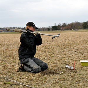 A woman is sitting on a field with a measuring instrument, photo.