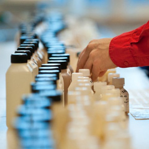 A hand at long rows of plastic containers, photo.