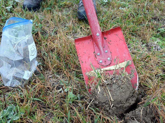 A red shovel with dirt on it, photo.
