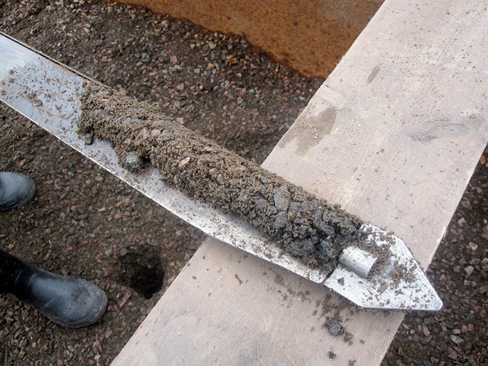 Soil on a narrow metal object, photo.