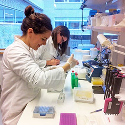 Two women pipetting in a lab, photo.