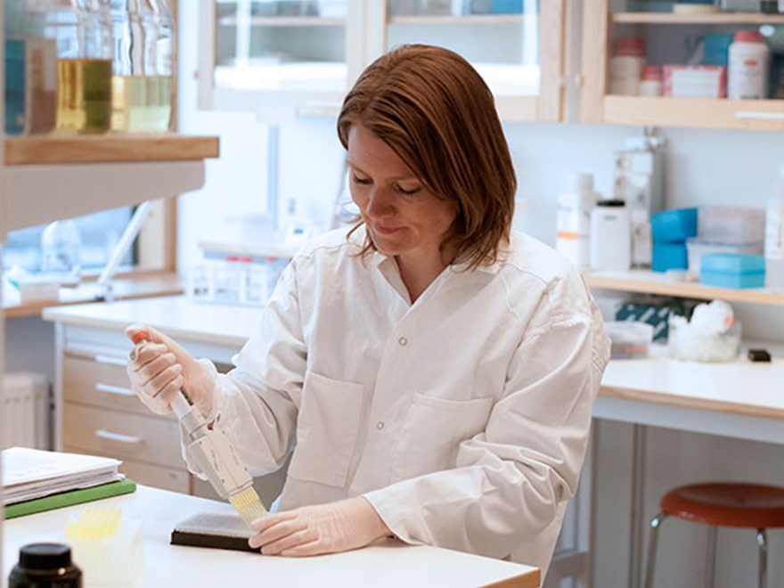 Woman pipetting in a lab, photo.