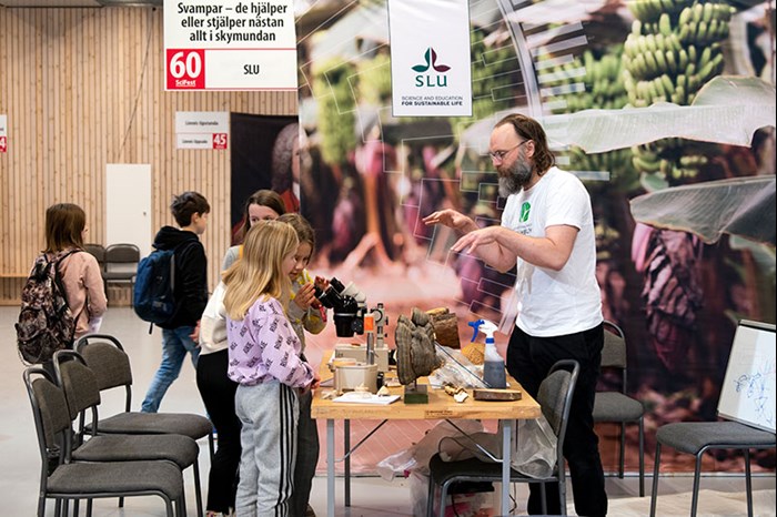 En forskare viftar med händerna framför en grupp mellanstadieelever, foto.