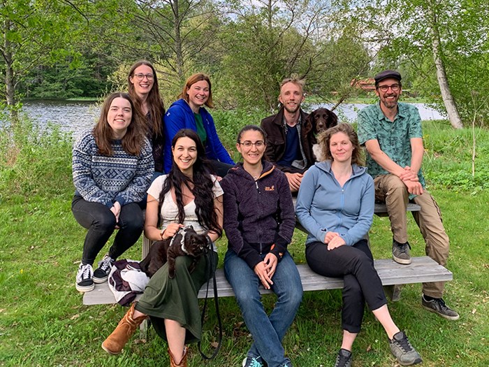 Eight people outdoors, looking into the camera. Photo.
