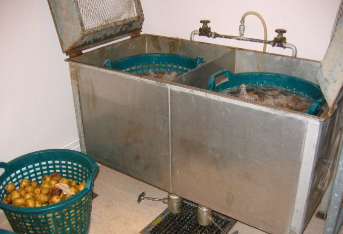 Stora kar med vatten som tvättar potatis med hjälp av tryckluft. Foto.