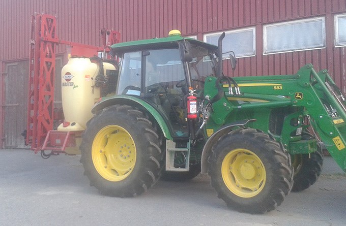 En traktor med en dunk bakom. Foto.