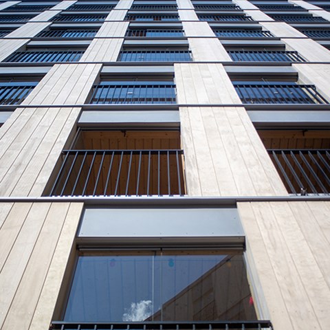 A wooden multistory building. The photo is taken close to the foot of the building looking up. 