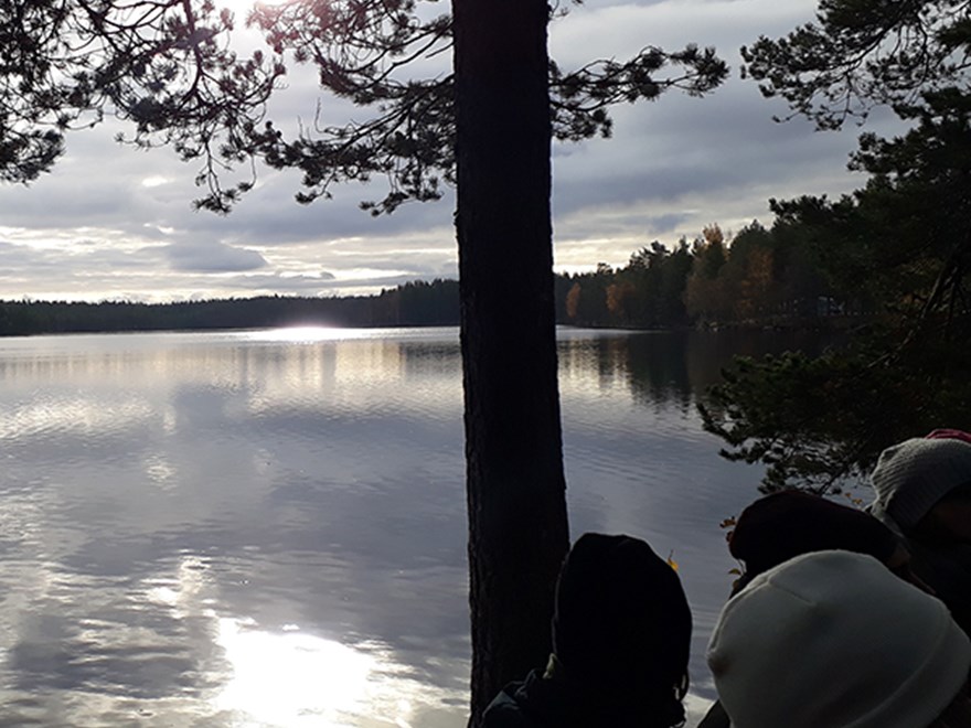 Foto på människor vid skogskantad sjö 