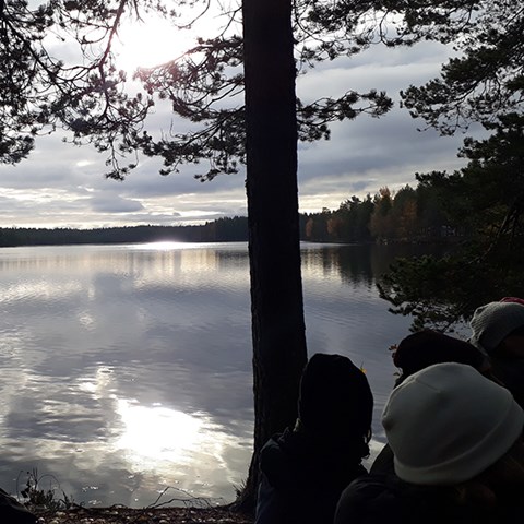 Photo of people by a lake surrounded by forest