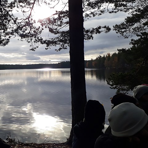 Foto på människor vid skogskantad sjö 