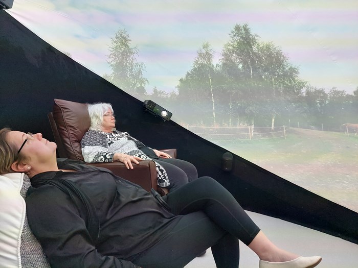 Två kvinnor sitter i en dome och tittar på vr-naturfilm