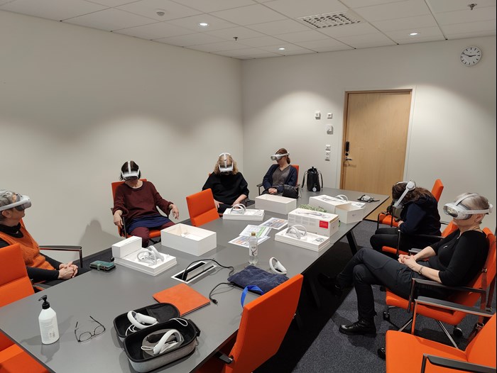 Five persons round a table with VR-glasses