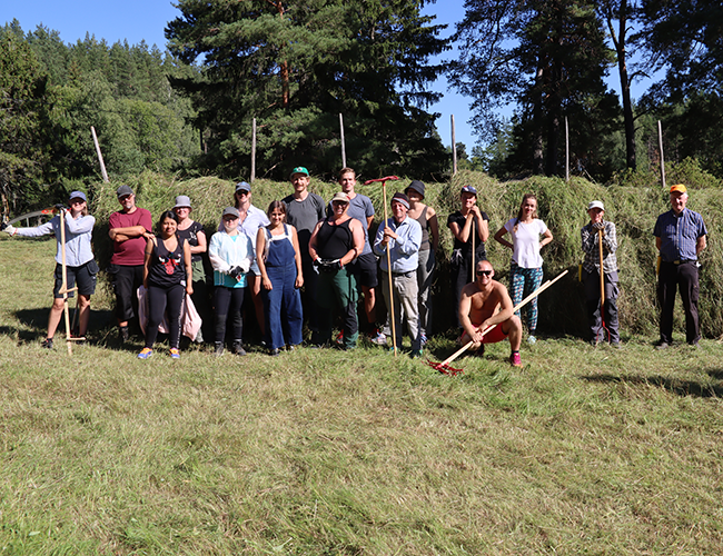 Particiapnts in the summer course, standing in front of the hay rack. Photo.