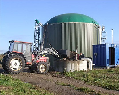 Traktor framför en biogassilo. Foto.