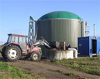 A tractor in front of a biogas silo. Photo.
