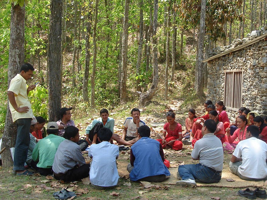 A group of local farmers in Nepal sitting on the ground for village discussions. Photo.