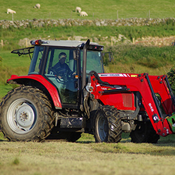 A red tractor on a field with sheep in the background. Photo.