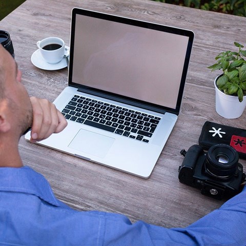 En man med en laptop och en kaffekopp